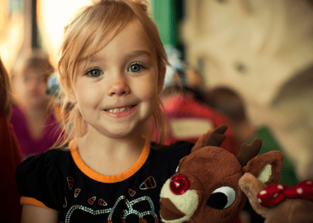 little girl holding a stuffed reindeer
